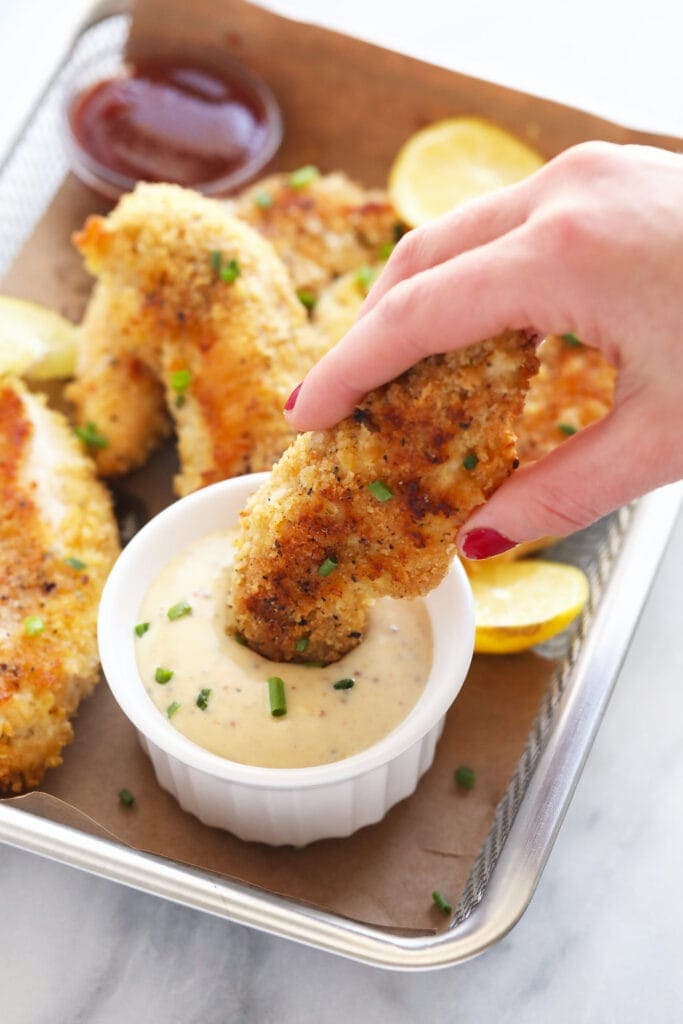 There's nothing better than crunchy, crispy baked chicken tenders. There is no need to deep fry these baked tenders, they are flavorful and crispy right out of the oven. chicken tenders dipping in honey mustard sauce