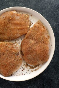 Seasoned chicken breasts on a plate.