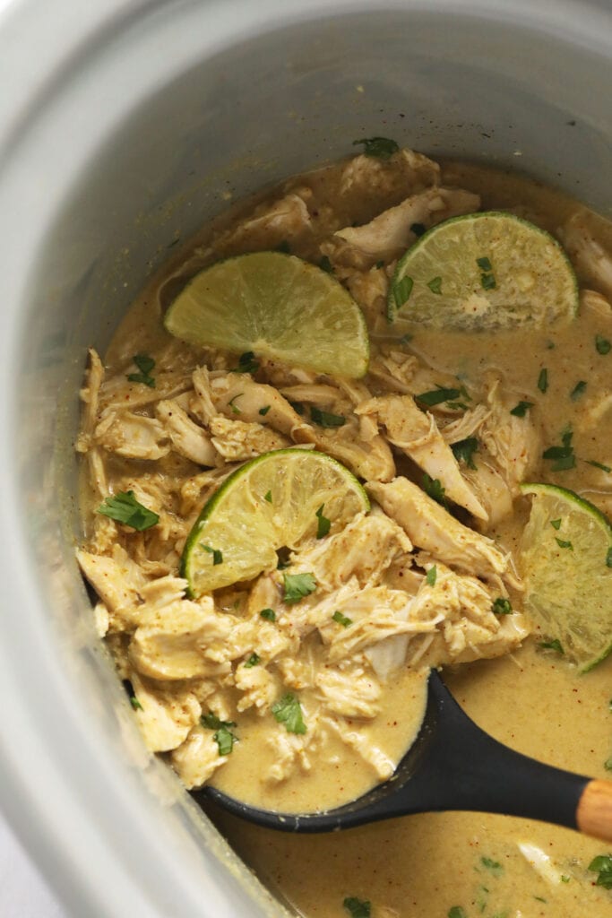 Coconut curry chicken in the slow cooker with fresh limes and cilantro in them. 