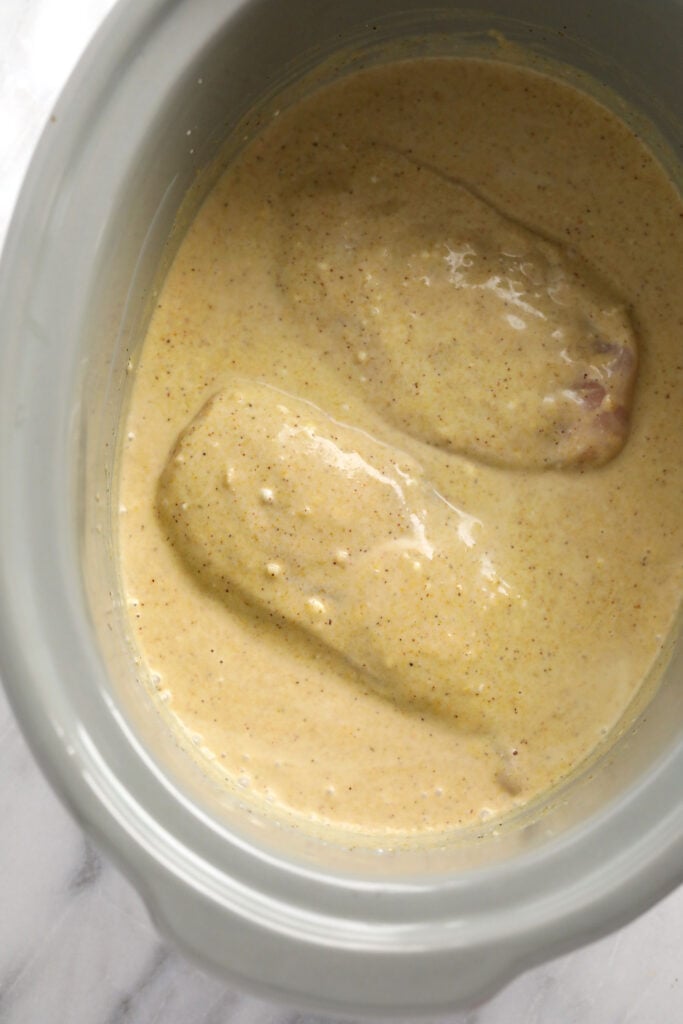 Chicken breasts in a slow cooker covered in coconut curry sauce. 