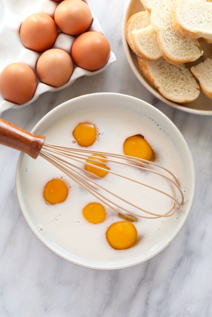 egg and milk in a bowl with a whisk