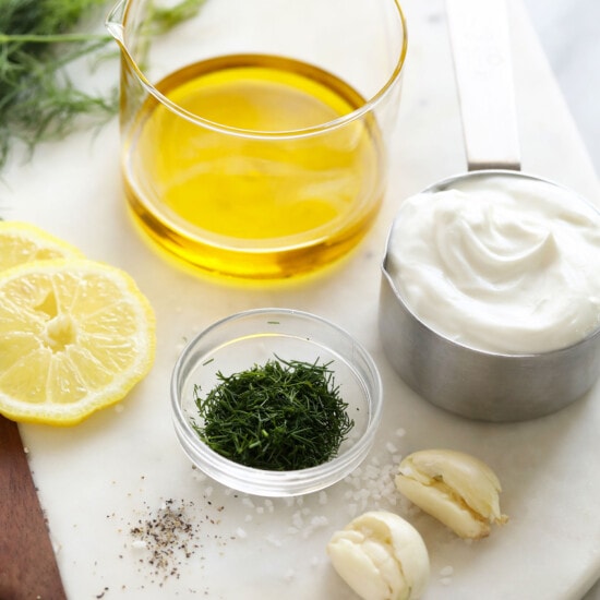 the ingredients for a dill dressing are on a cutting board.