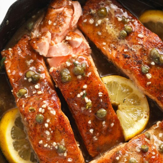 salmon fillets in a skillet with lemon and capers.