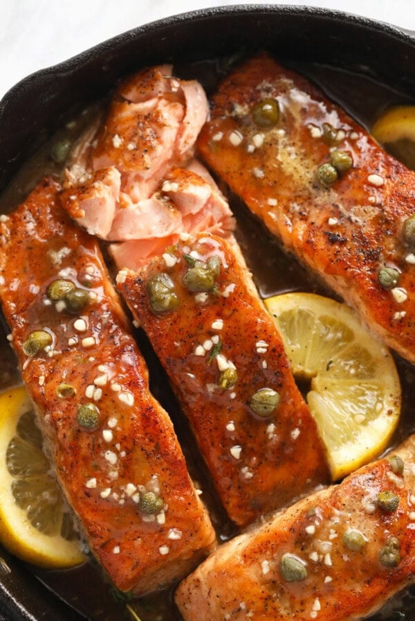 salmon fillets in a skillet with lemon and capers.