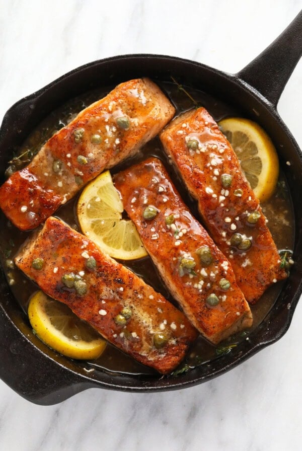 Salmon piccata in a cast iron with lemons, capers, and garlic.