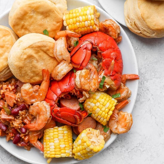 a plate with shrimp, corn, and biscuits.