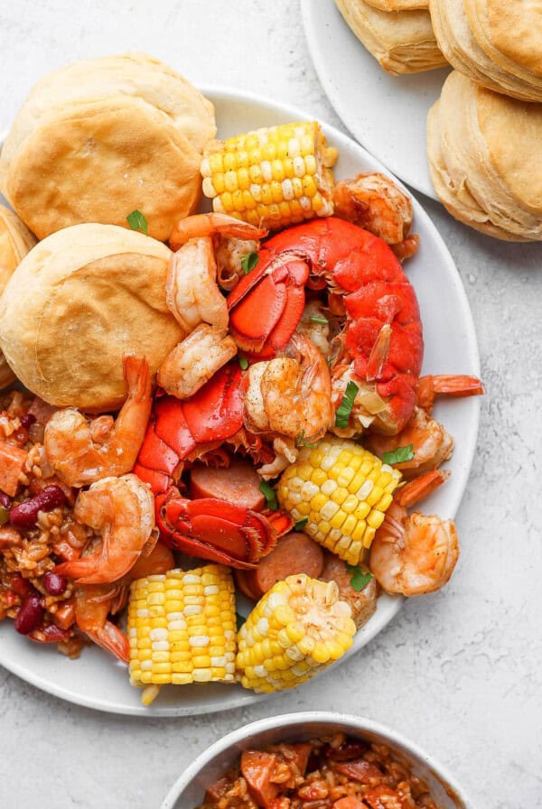 a plate with shrimp, corn, and biscuits.