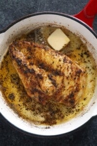 A frying pan with a piece of chicken in it.