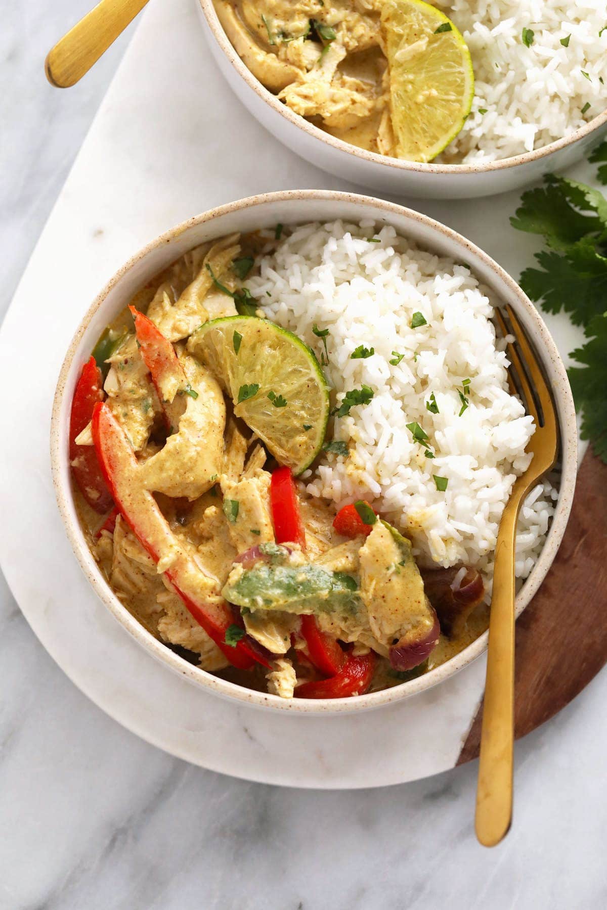 Coconut curry chicken in a bowl with rice, peppers, and onions. 