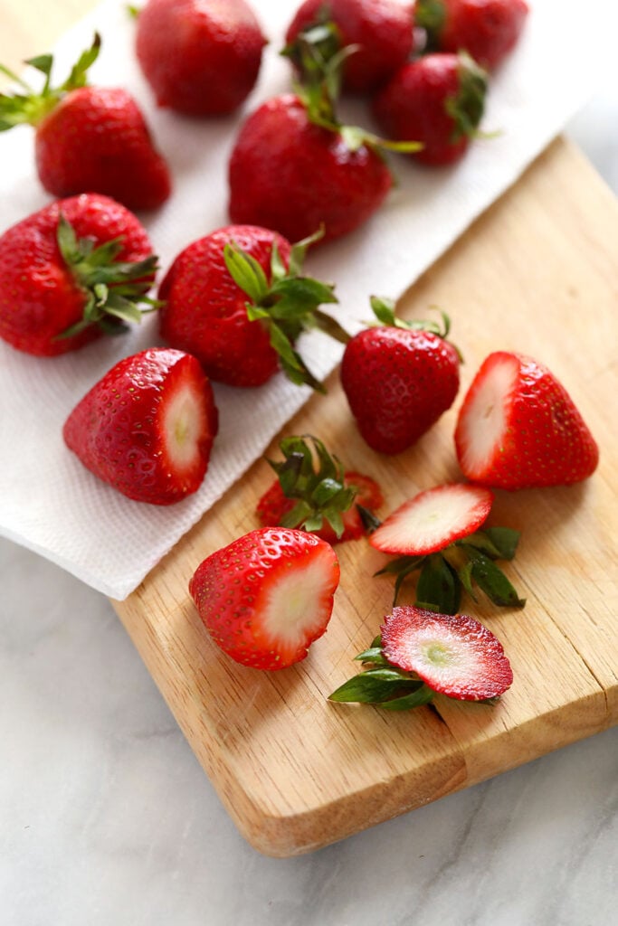 Cutting the tops off fresh strawberries before freezing them. 