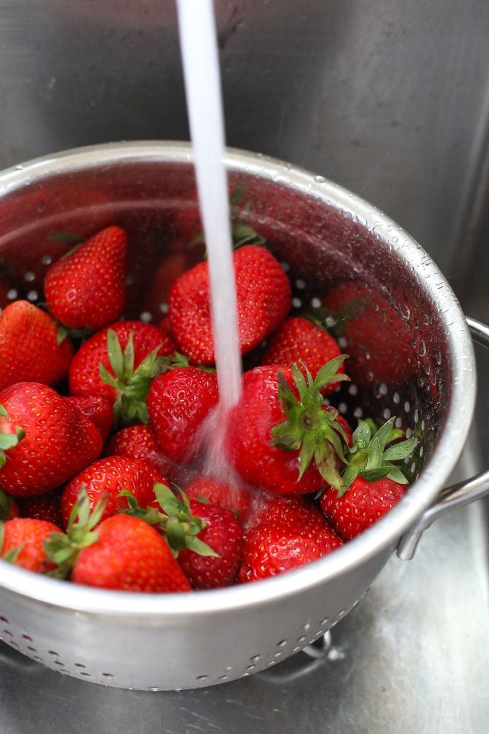 Rinsing fresh strawberries with water. 