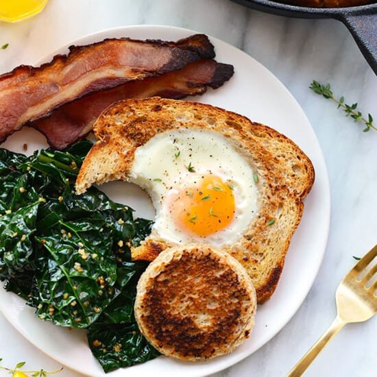 a plate with bacon, eggs and kale on it.