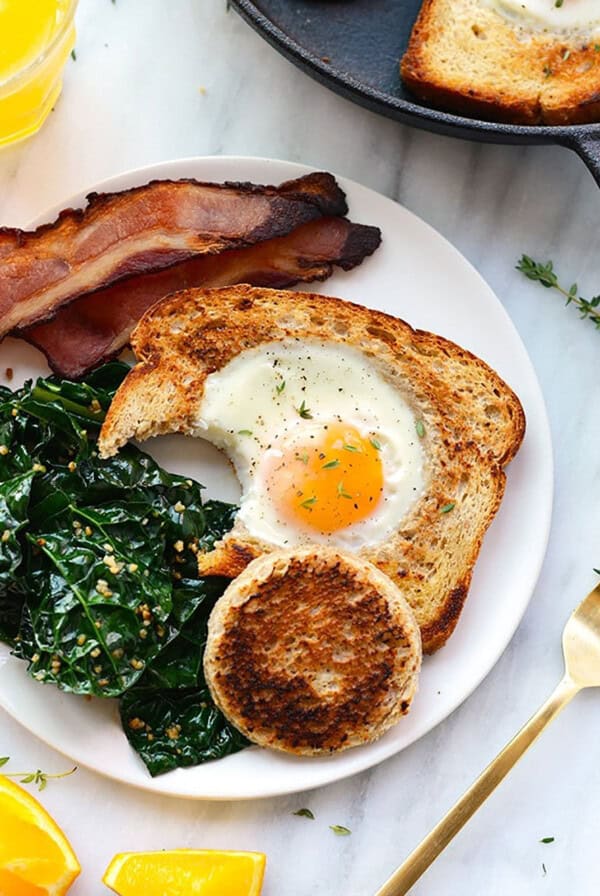 a plate with bacon, eggs and kale on it.