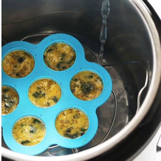 An air fryer filled with eggs in a muffin tin.