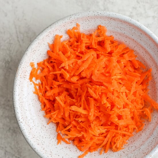 shredded carrots in a white bowl.