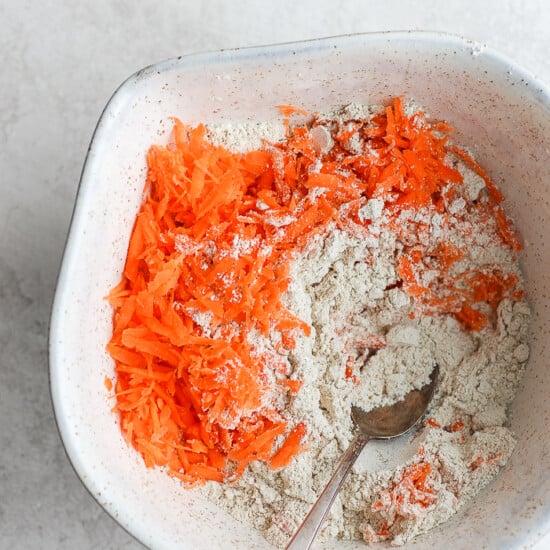 a white bowl with carrots and flour in it.