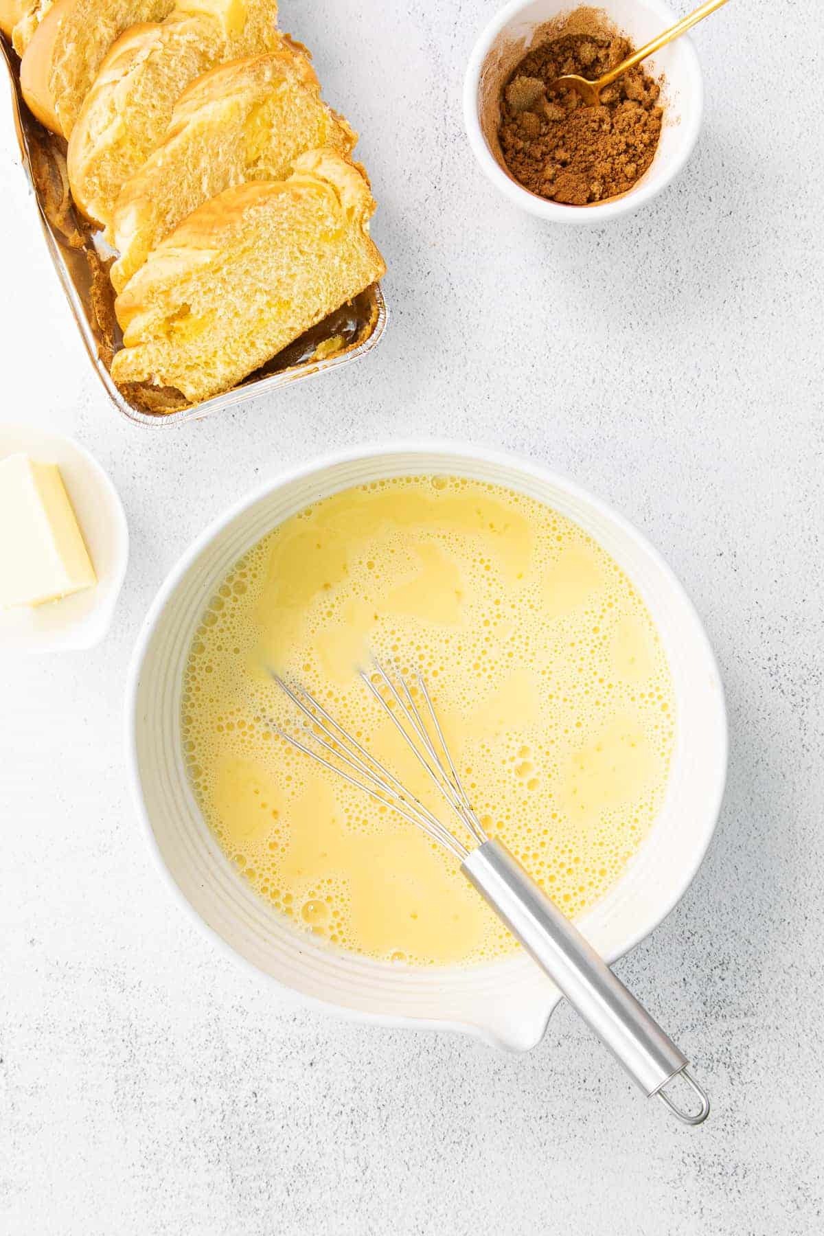 egg wash for french toast in a bowl with slices of bread next to it