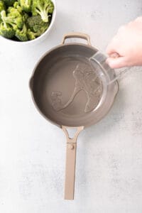 a person pouring water into a frying pan.