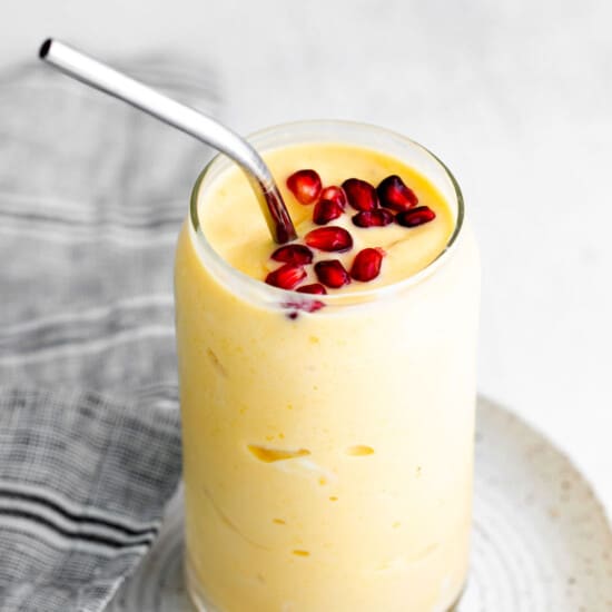 a banana smoothie with pomegranate on a white plate.