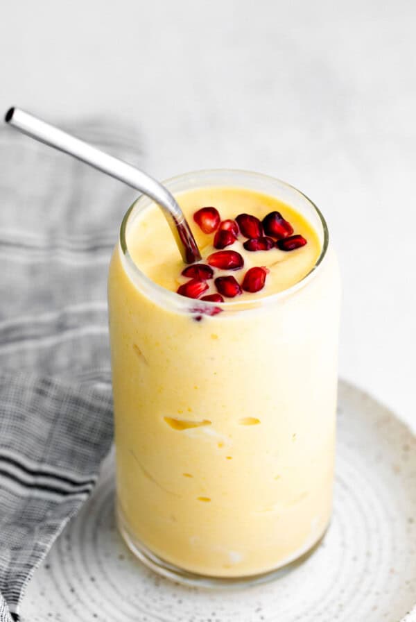 a banana smoothie with pomegranate on a white plate.