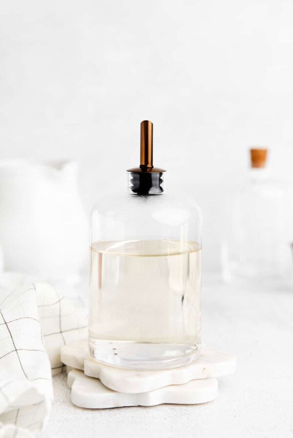 a glass bottle with a wooden handle sits on a table.