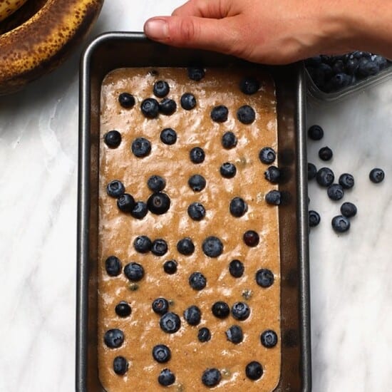 A person holding a pan of blueberry banana bread.