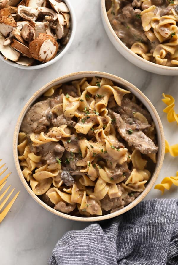 Two bowls of delicious Swedish beef stroganoff beautifully displayed on a marble table.