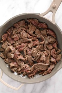 A skillet full of beef stroganoff on a marble countertop.