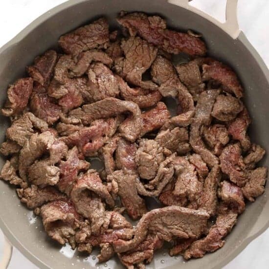 A skillet full of beef stroganoff on a marble countertop.