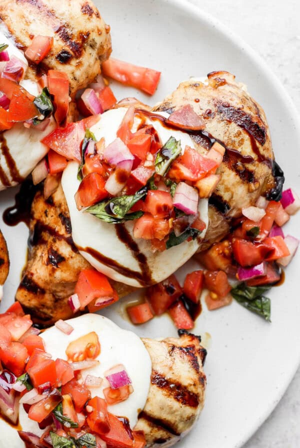 a white plate topped with grilled chicken covered in salsa.