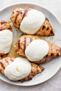 a white plate topped with chicken breasts covered in ice cream.