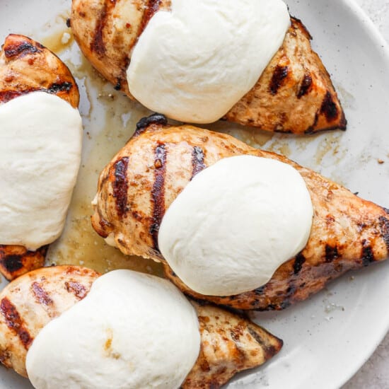 a white plate topped with chicken breasts covered in ice cream.