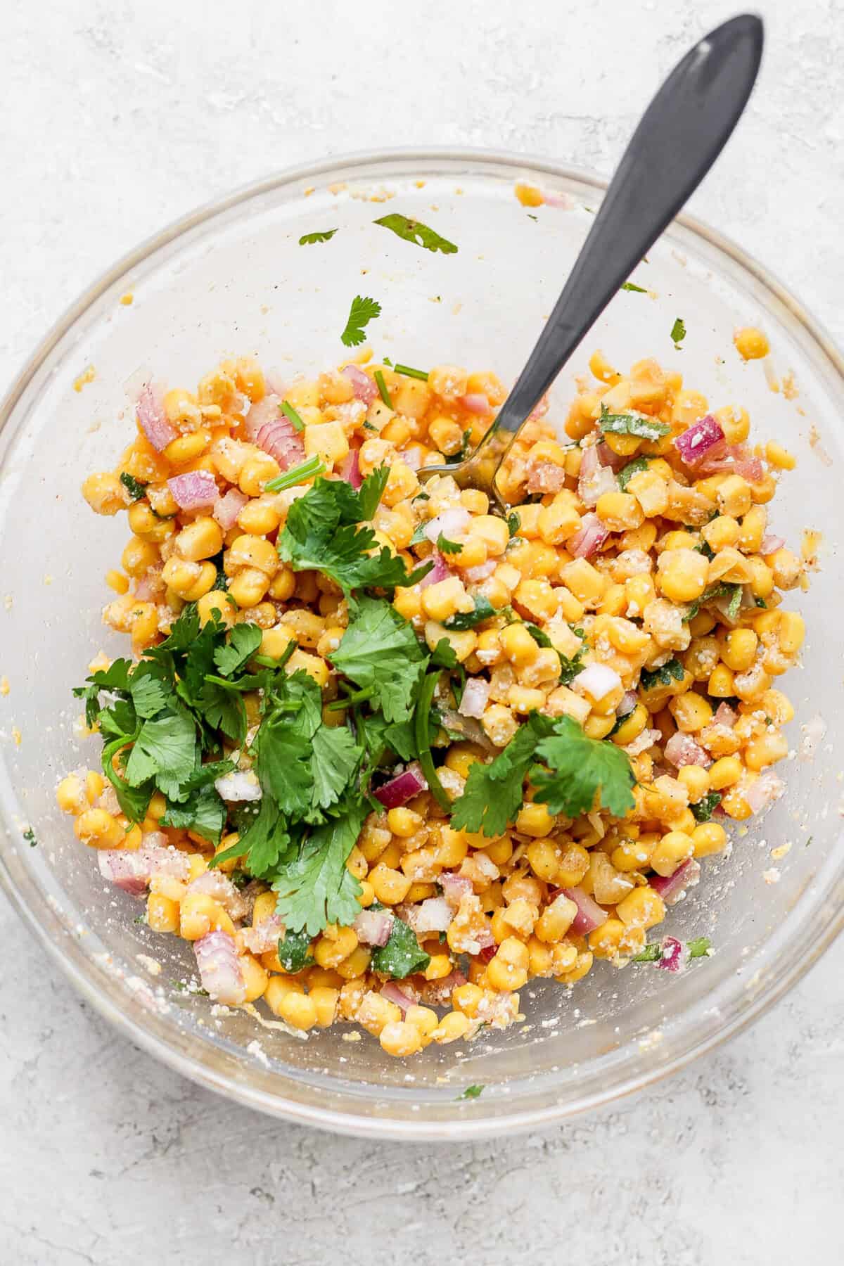 Mexican corn salad with slow cooker carnitas served in a glass bowl.