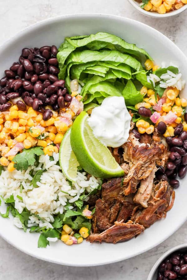 a bowl of mexican pulled pork salad with black beans, rice and sour cream.