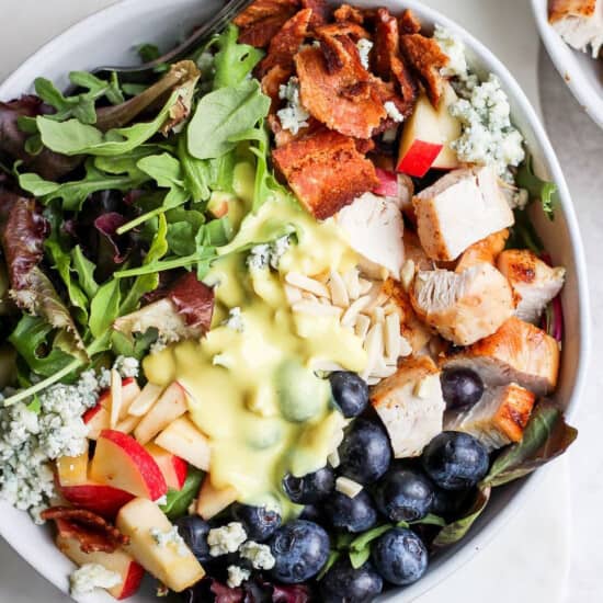 a bowl of chicken salad with blueberries and bacon.