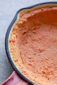 Close-up of a sweet potato crust quiche in a red baking dish with a partially visible black rim.