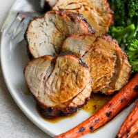 sliced pork on plate with broccoli and carrots