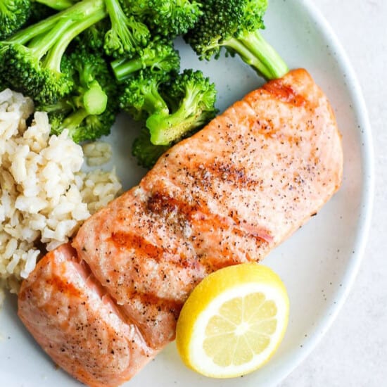 grilled salmon on a plate with broccoli and rice.