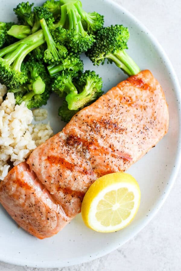 grilled salmon on a plate with broccoli and rice.