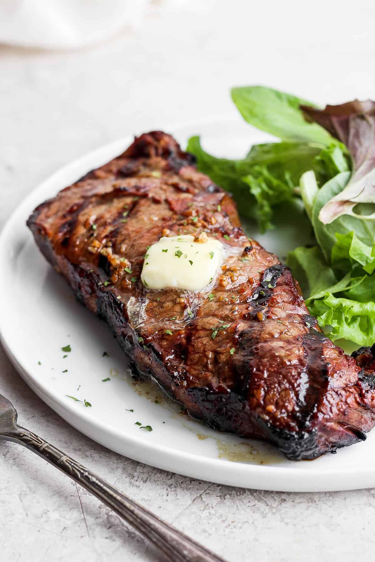 steak on a plate with greens.