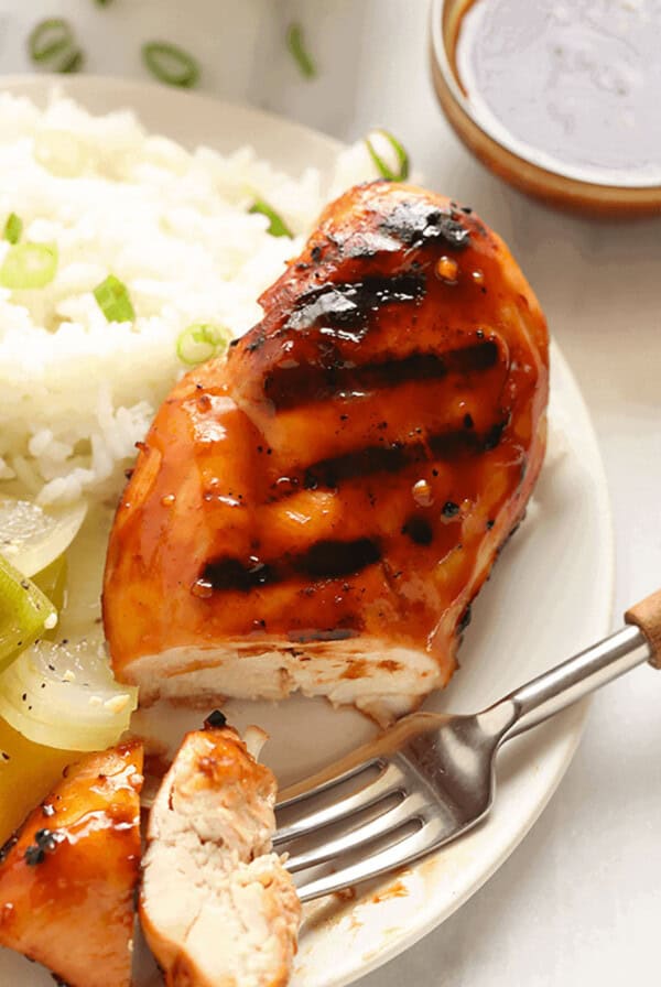 a white plate topped with chicken, rice and vegetables.