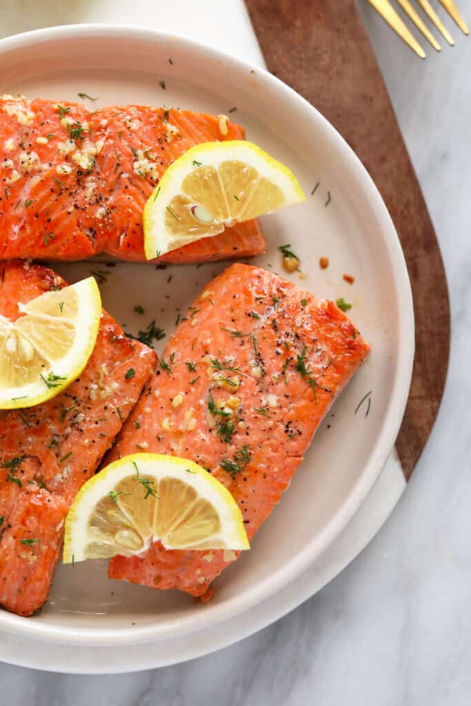 seared salmon on plate with lemon wedges.