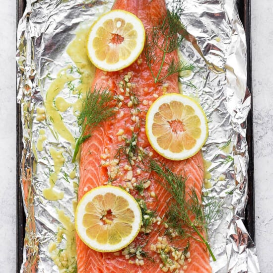salmon on top of foil with dill and lemons.