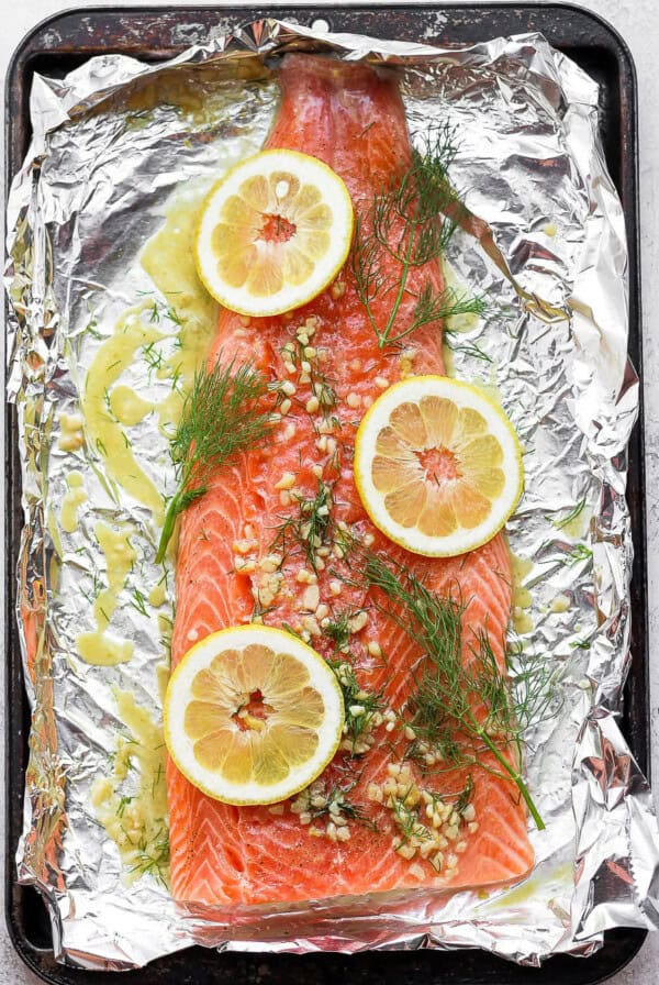 salmon on top of foil with dill and lemons.