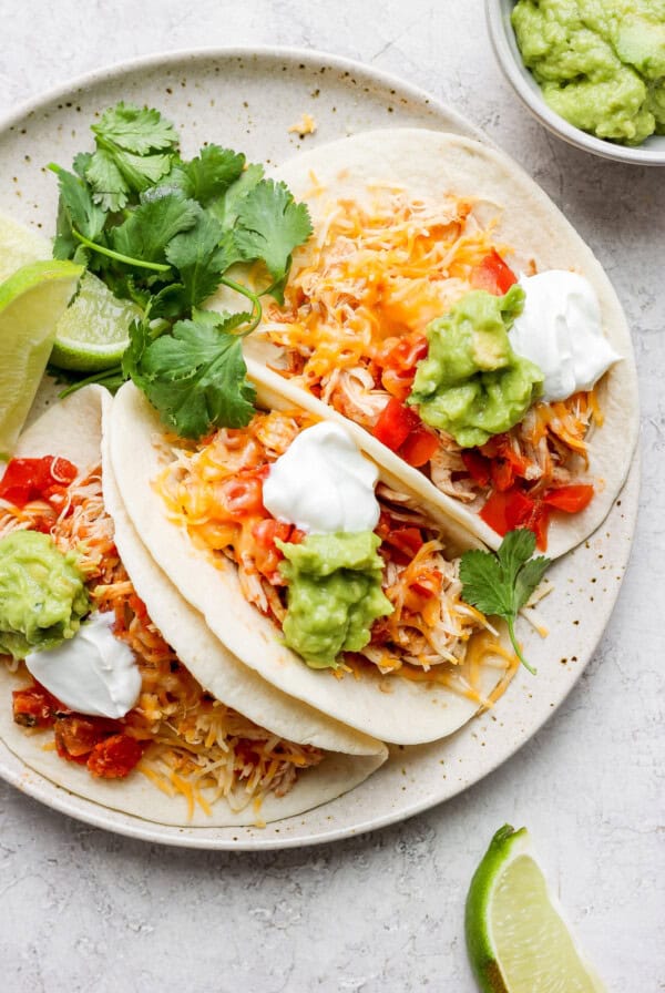 Shredded chicken tacos topped with guacamole and sour cream.