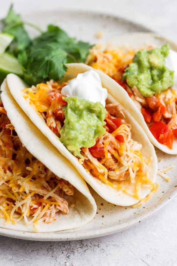 chicken tacos with cheese and guacamole on plate.