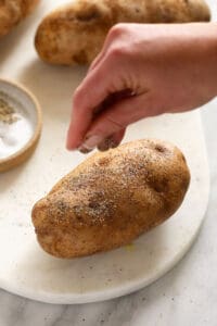 a person is sprinkling salt on some potatoes.