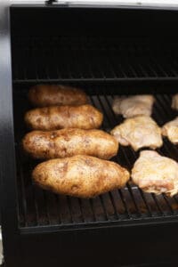 a bbq grill with chicken and potatoes on it.