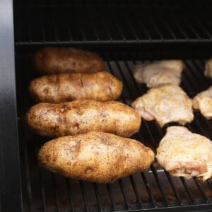 a bbq grill with chicken and potatoes on it.