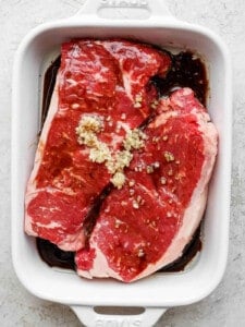 steak marinading in dish.